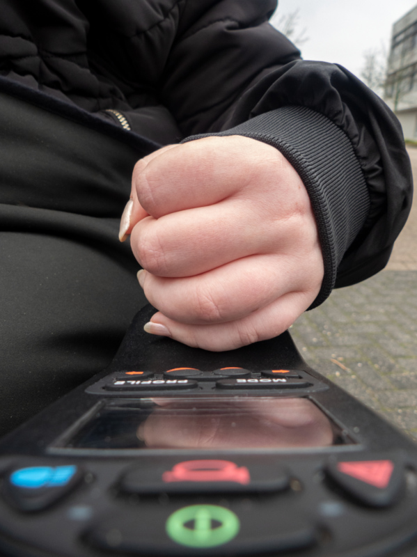 Die Steuerung des elektrischen Rollstuhls, der Steuergriff umschlossen von der Hand der Studentin
