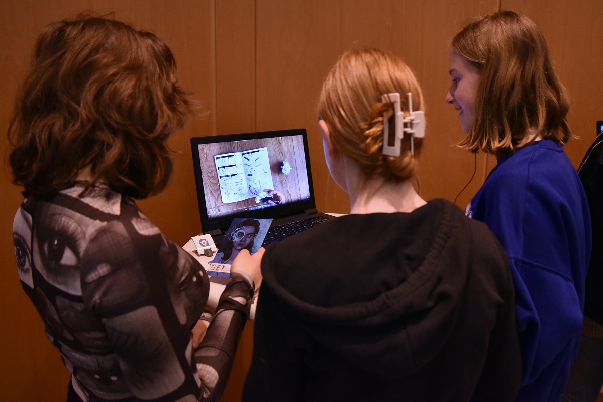 Mädchen sehen sich auf einem Laptop die von Schülerinnen produzierten Videos an