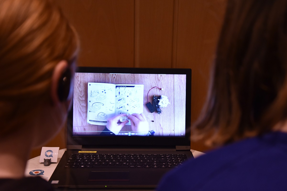 Mädchen sehen sich auf einem Laptop die von Schülerinnen produzierten Videos an