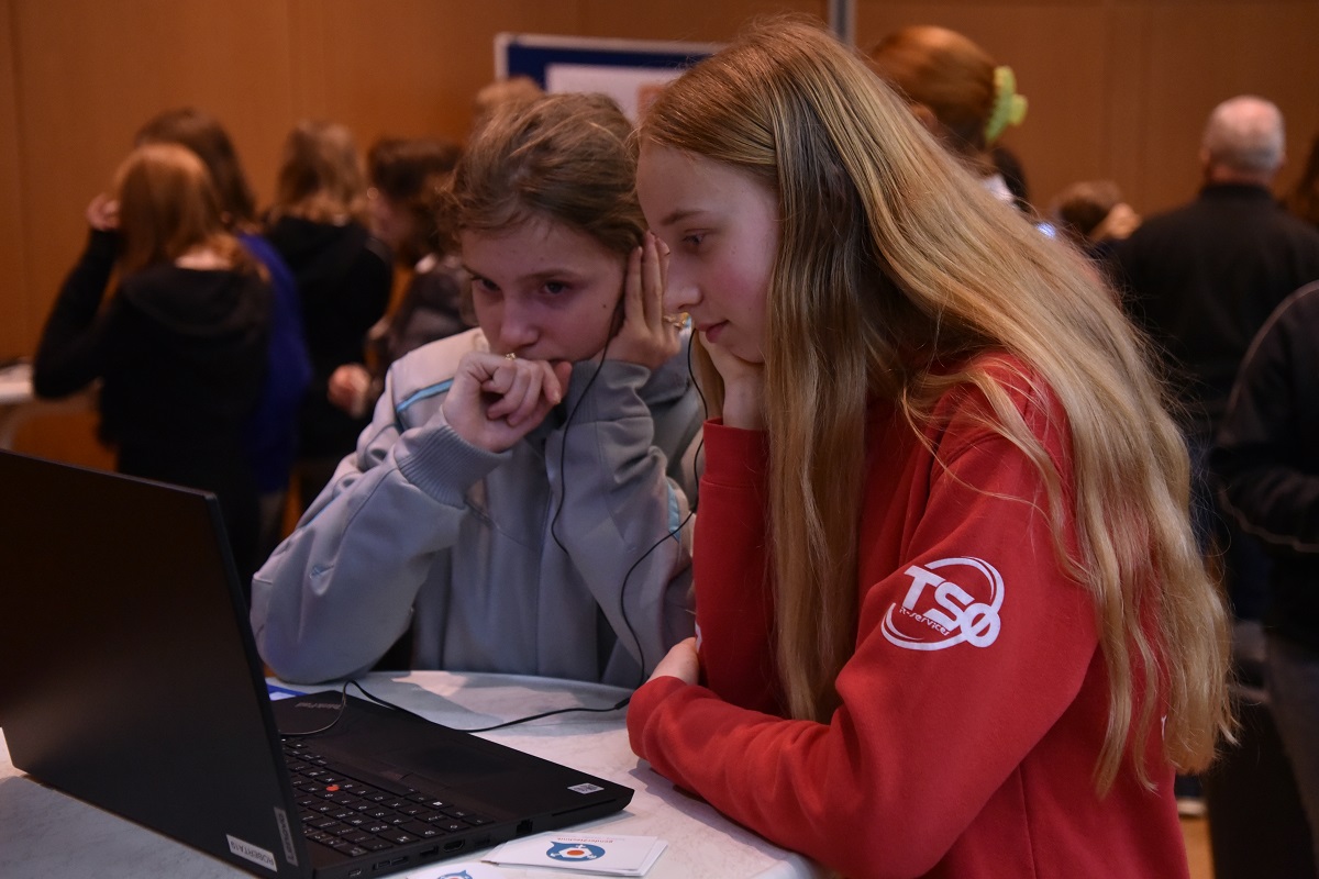 Mädchen sehen sich auf einem Laptop die von Schülerinnen produzierten Videos an